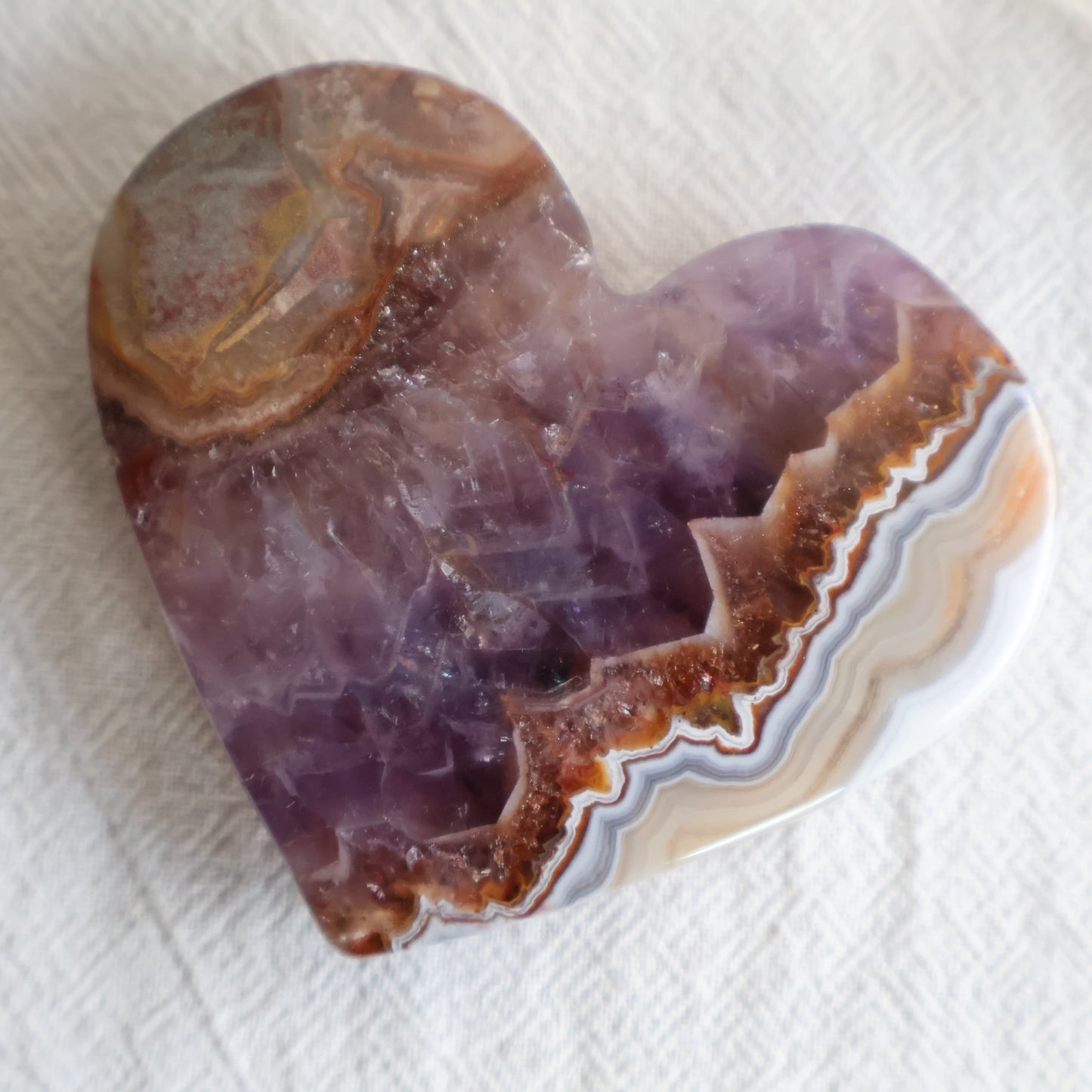 Amethyst Agate crystal heart with purple crystalline centre, brown and white natural banding and clear chair display stand.
