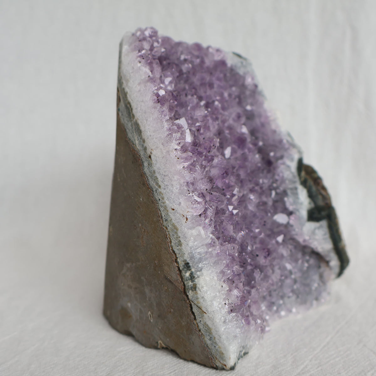 Natural Amethyst druzy cut base weighing 998g with purple crystal points and raw outer edges, standing 11.5cm tall.