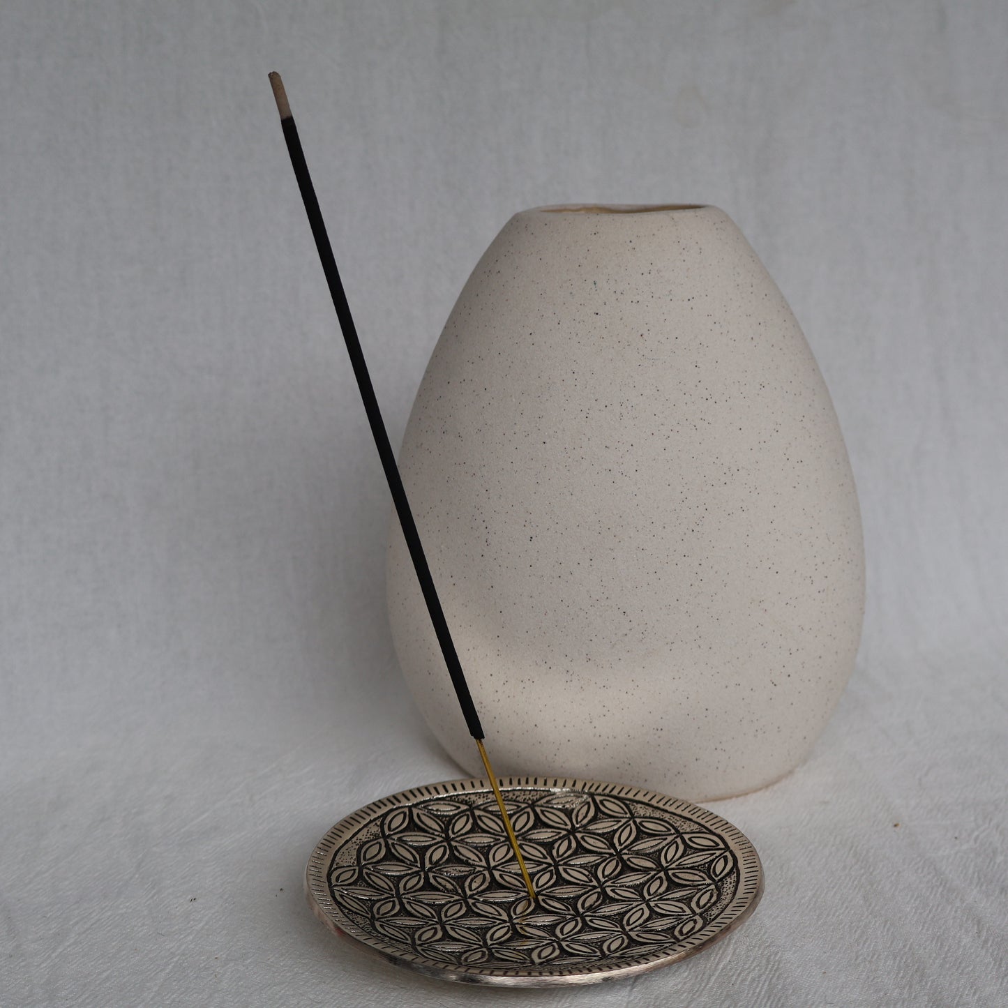 Ceramic incense holder with a patterned base and a plain white background