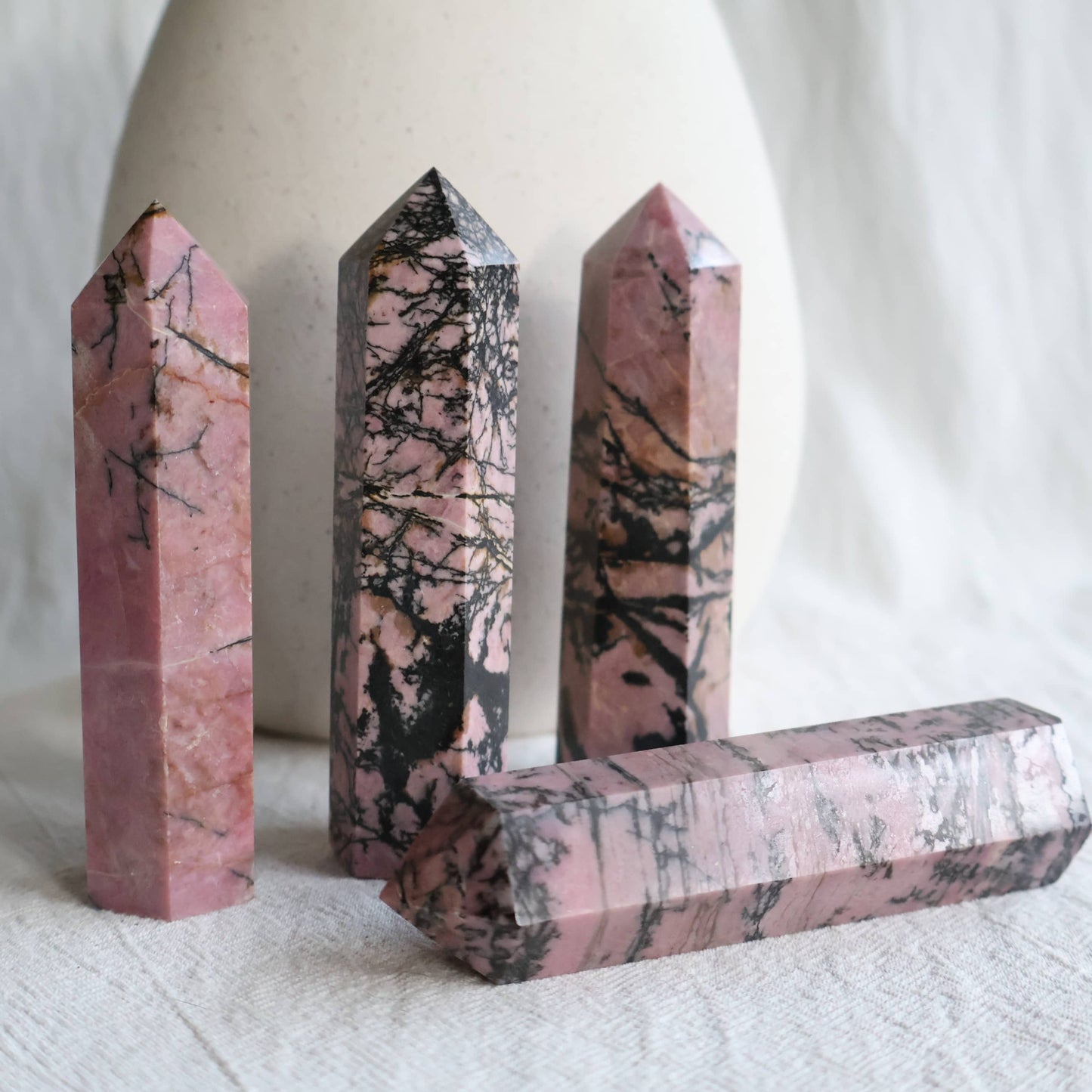 Pink Rhodonite crystal generator with natural black manganese veining and earthy patterning, polished into a pointed tower.
