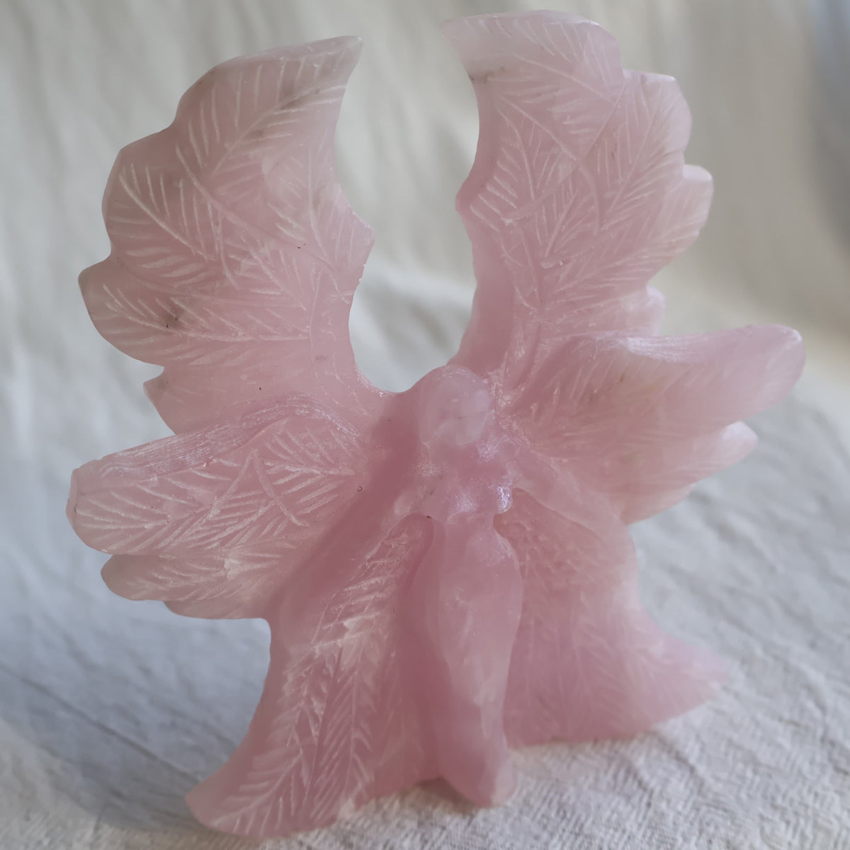 Large Rose Quartz angel crystal carving, 12cm tall and 11cm wide, with detailed feathered wings.