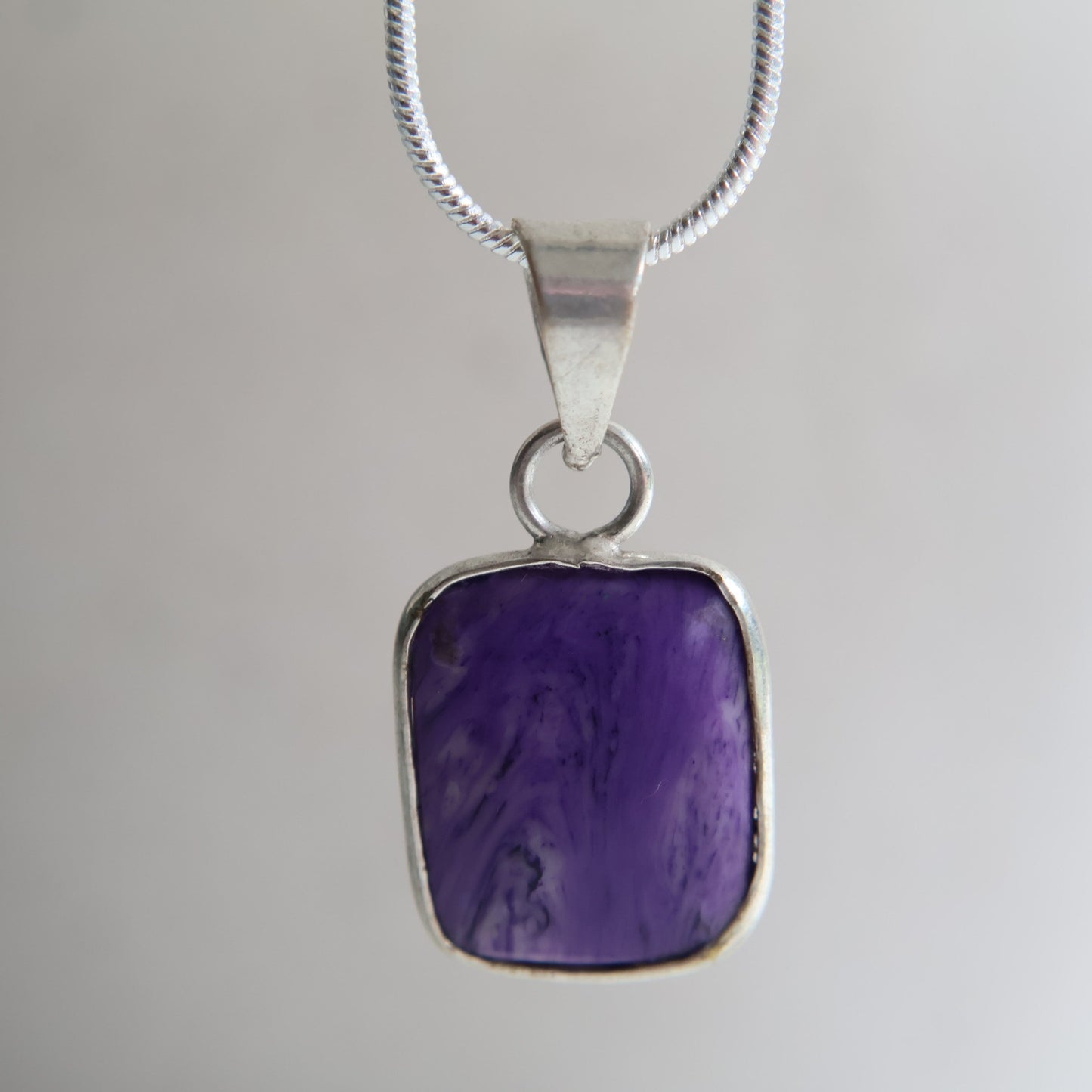 Charoite crystal pendant with rich purple swirling patterns and wrapped s925 silver border, exact piece shown