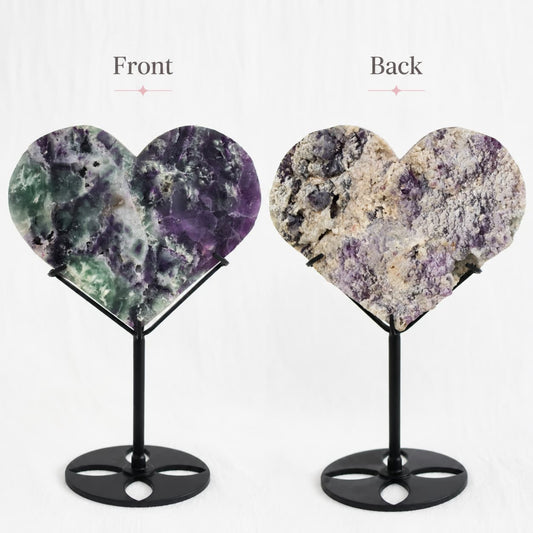 Large purple and green Fluorite heart on black stand with a roughly polished face and contrasting raw crystal reverse, 23cm tall on stand.