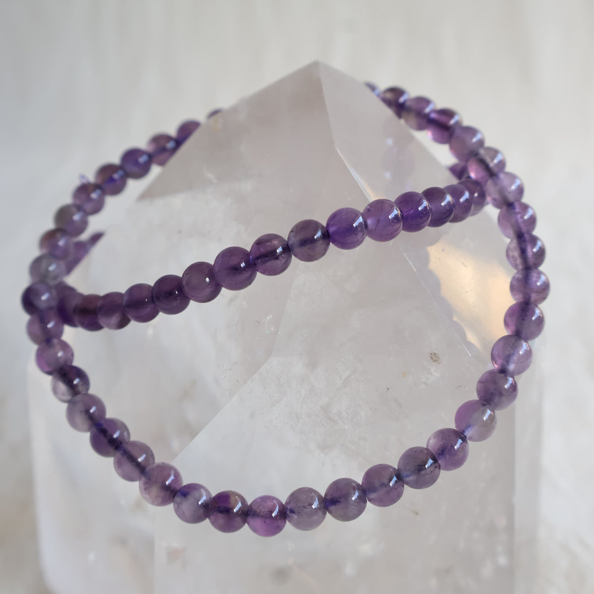 Amethyst crystal bracelet with polished 4mm round beads on a stretch fit band.