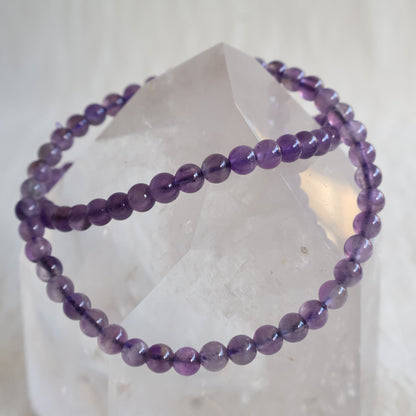 Amethyst crystal bracelet with polished 4mm round beads on a stretch fit band.