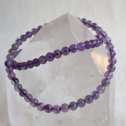 Amethyst crystal bracelet with polished 4mm round beads on a stretch fit band.