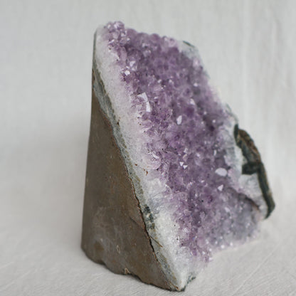 Natural Amethyst druzy cut base weighing 998g with purple crystal points and raw outer edges, standing 11.5cm tall.