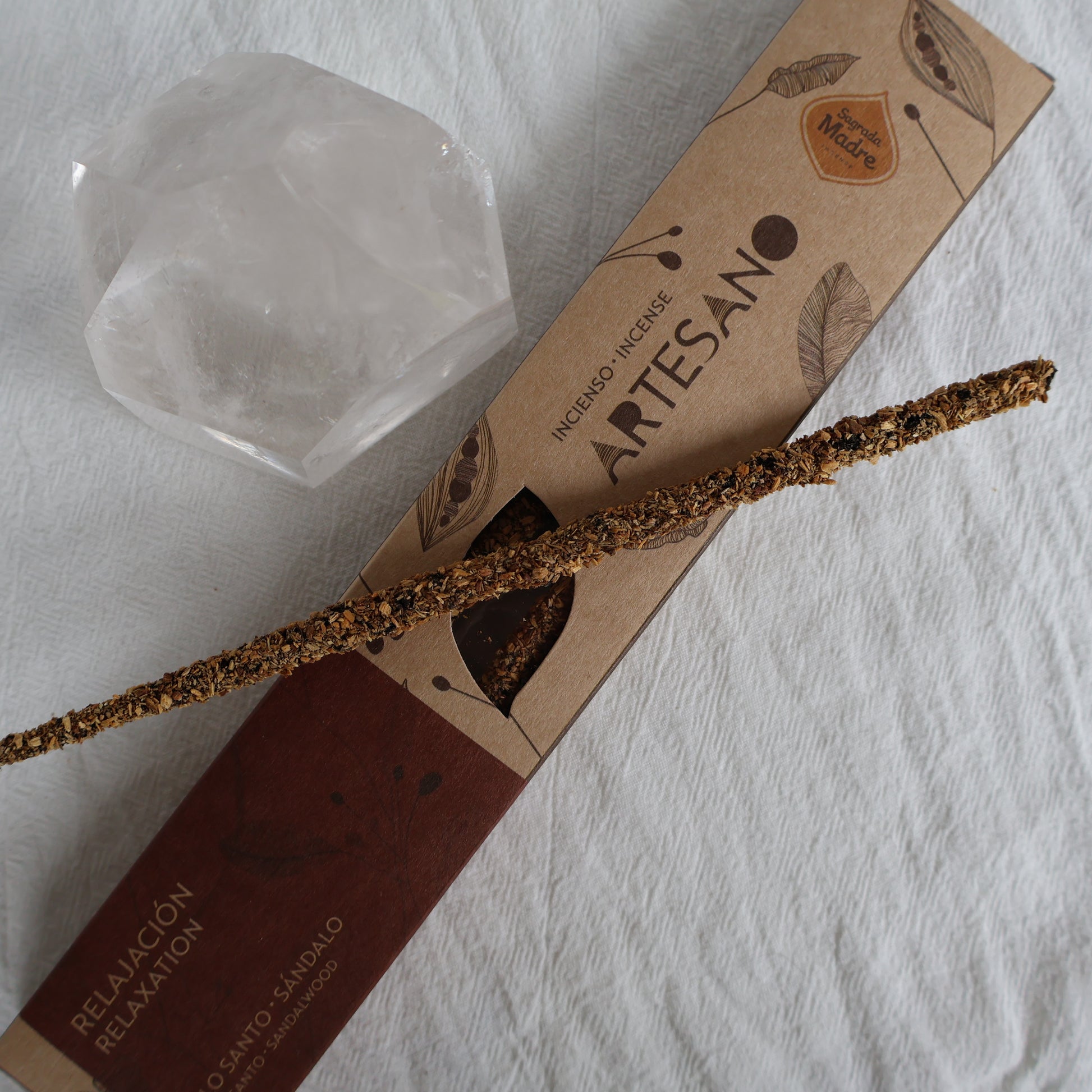 Artisanal incense stick with packaging and a crystal on a white surface