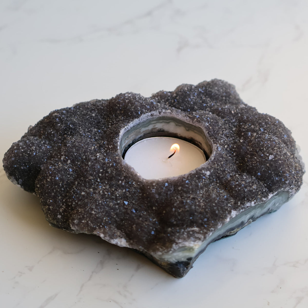Black Amethyst tealight candle holder, 14cm long and 586g, with a dark natural druzy crystal surface and carved candle opening.