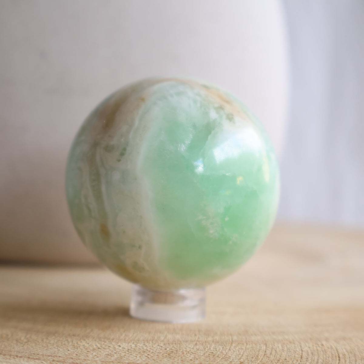 Caribbean Calcite crystal sphere, 4.4cm and 133g, with soft blue-green colouring and natural cream and sandy-toned banding.
