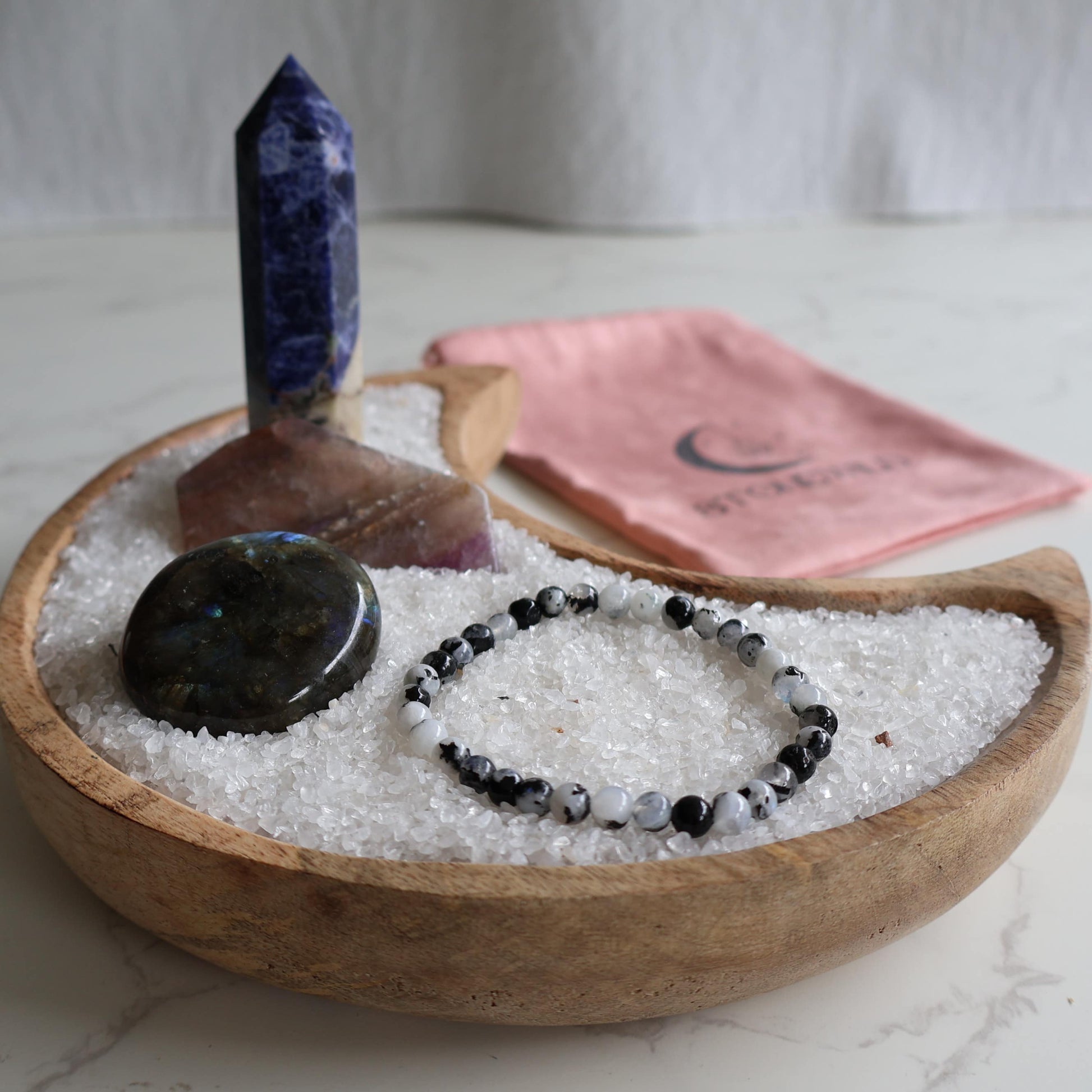 Intuition and balance ritual set with sodalite generator labradorite palm rainbow moonstone bracelet and fluorite slice in Stonewild drawstring bag.