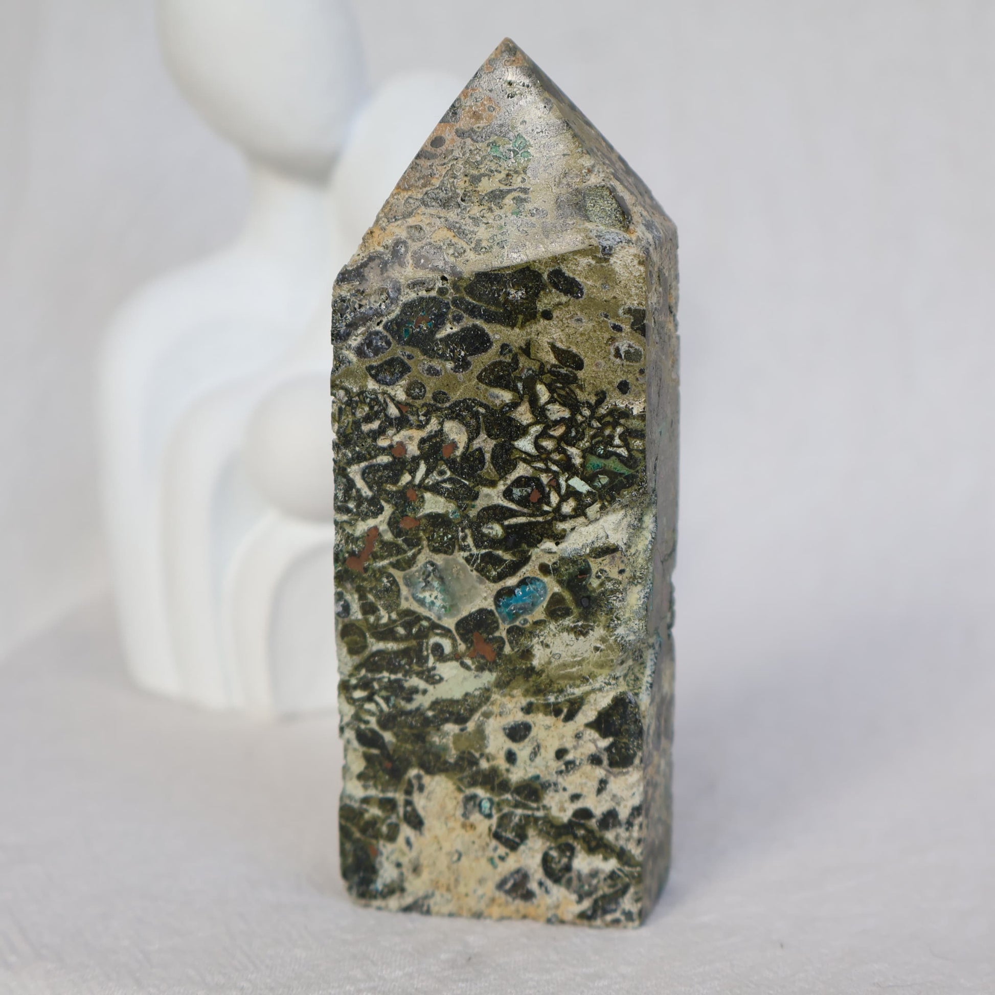 Epidote obelisk with natural Chrysocolla and copper inclusions, featuring earthy green, soft blue and metallic tones, 10.7cm tall.