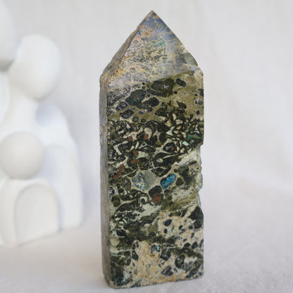 Epidote obelisk with natural Chrysocolla and copper inclusions, featuring earthy green, soft blue and metallic tones, 10.7cm tall.