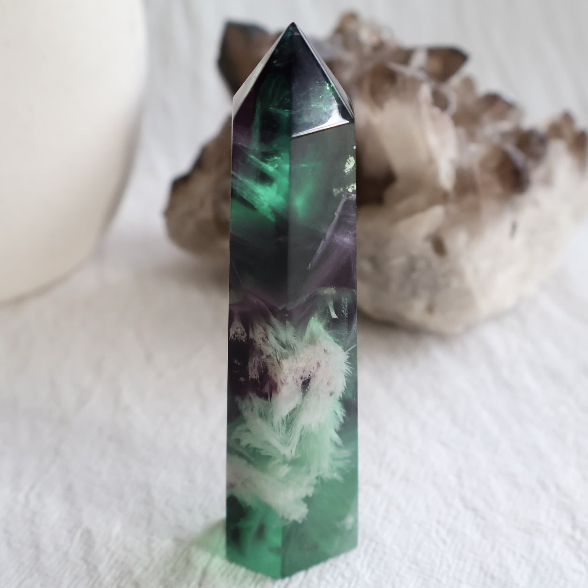 Purple and green Feather Fluorite tower with white feather-like mineral inclusions, translucent colour zoning and polished point