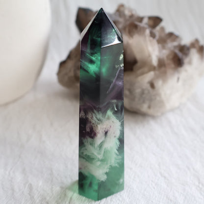 Purple and green Feather Fluorite tower with white feather-like mineral inclusions, translucent colour zoning and polished point