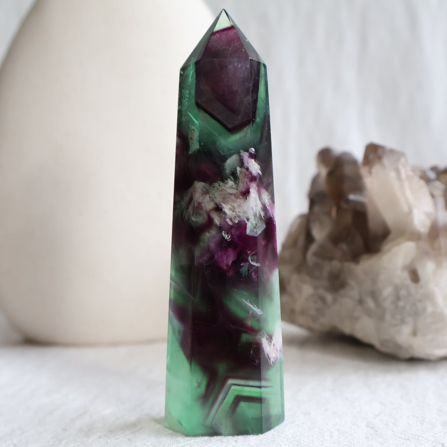 Purple and green Feather Fluorite tower with white feather-like mineral inclusions, translucent colour zoning and polished point