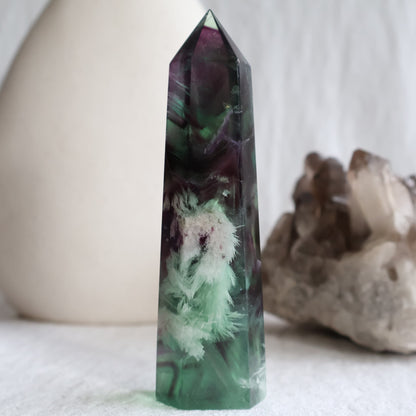 Purple and green Feather Fluorite tower with white feather-like mineral inclusions, translucent colour zoning and polished point