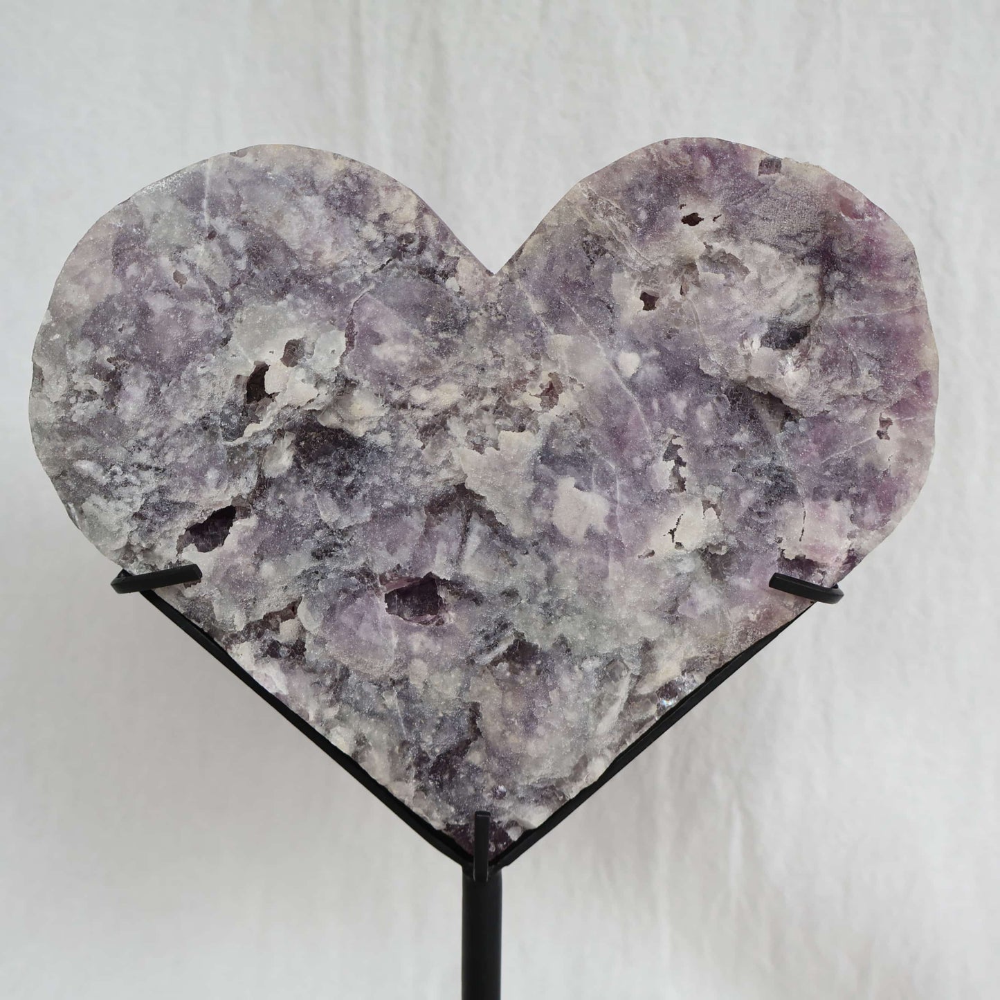 Large teal-green and purple Fluorite heart on black stand with a roughly polished face and contrasting raw lavender crystal reverse, 23cm tall.