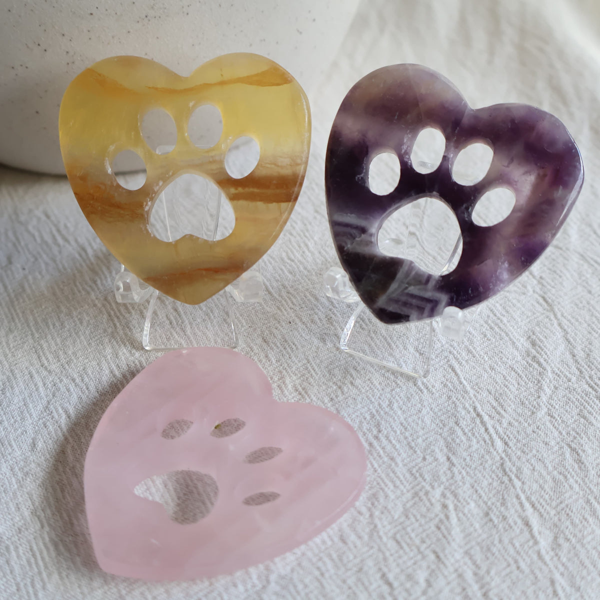 Crystal heart carvings with paw print cut-outs, available in Rose Quartz, Fluorite and Dream Amethyst.