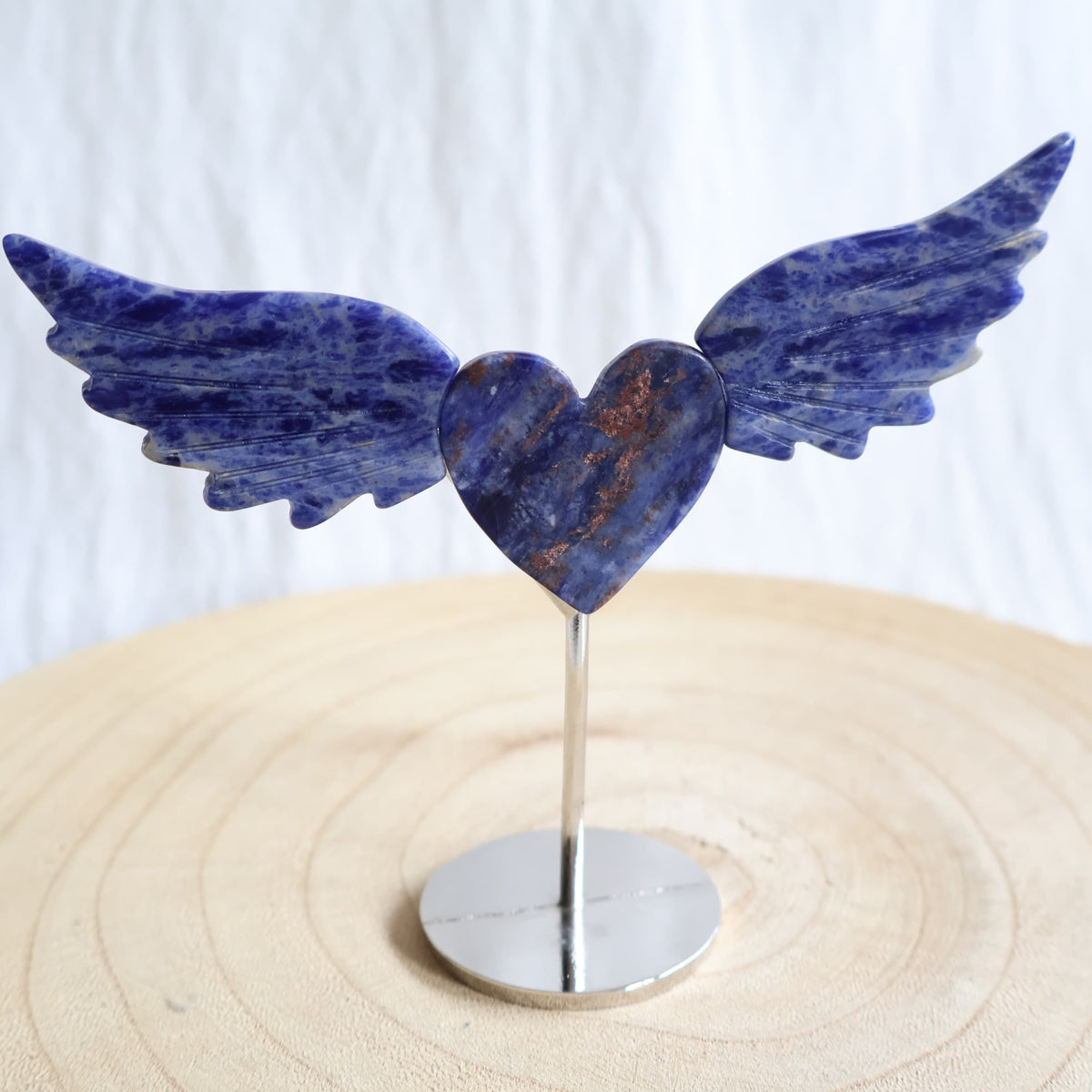 Crystal heart with carved wings in natural Moss Agate, Sodalite, Fire Quartz or Amethyst Agate, displayed upright on a silver-toned stand.