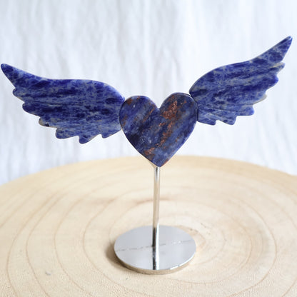 Crystal heart with carved wings in natural Moss Agate, Sodalite, Fire Quartz or Amethyst Agate, displayed upright on a silver-toned stand.