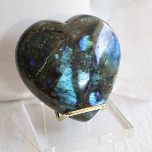 Labradorite crystal heart with bright blue and teal flash on a gold-toned display stand.