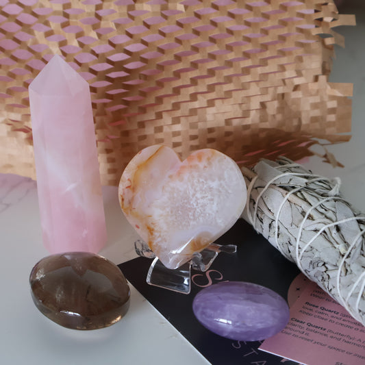 Love Within Valentine’s self love ritual set gift box with Rose Quartz generator, Flower Agate heart on stand, Smoky Quartz palm stone, Amethyst tumble, and sage bundle