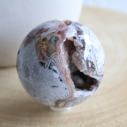 Crazy Lace Agate crystal sphere with natural banding and open druzy Quartz cavity, measuring 5cm and weighing 190g.