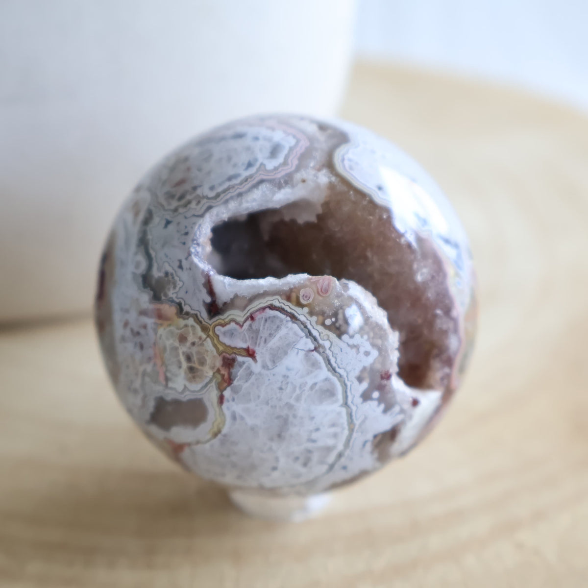 Crazy Lace Agate crystal sphere with natural banding and open druzy Quartz cavity, measuring 5cm and weighing 190g.