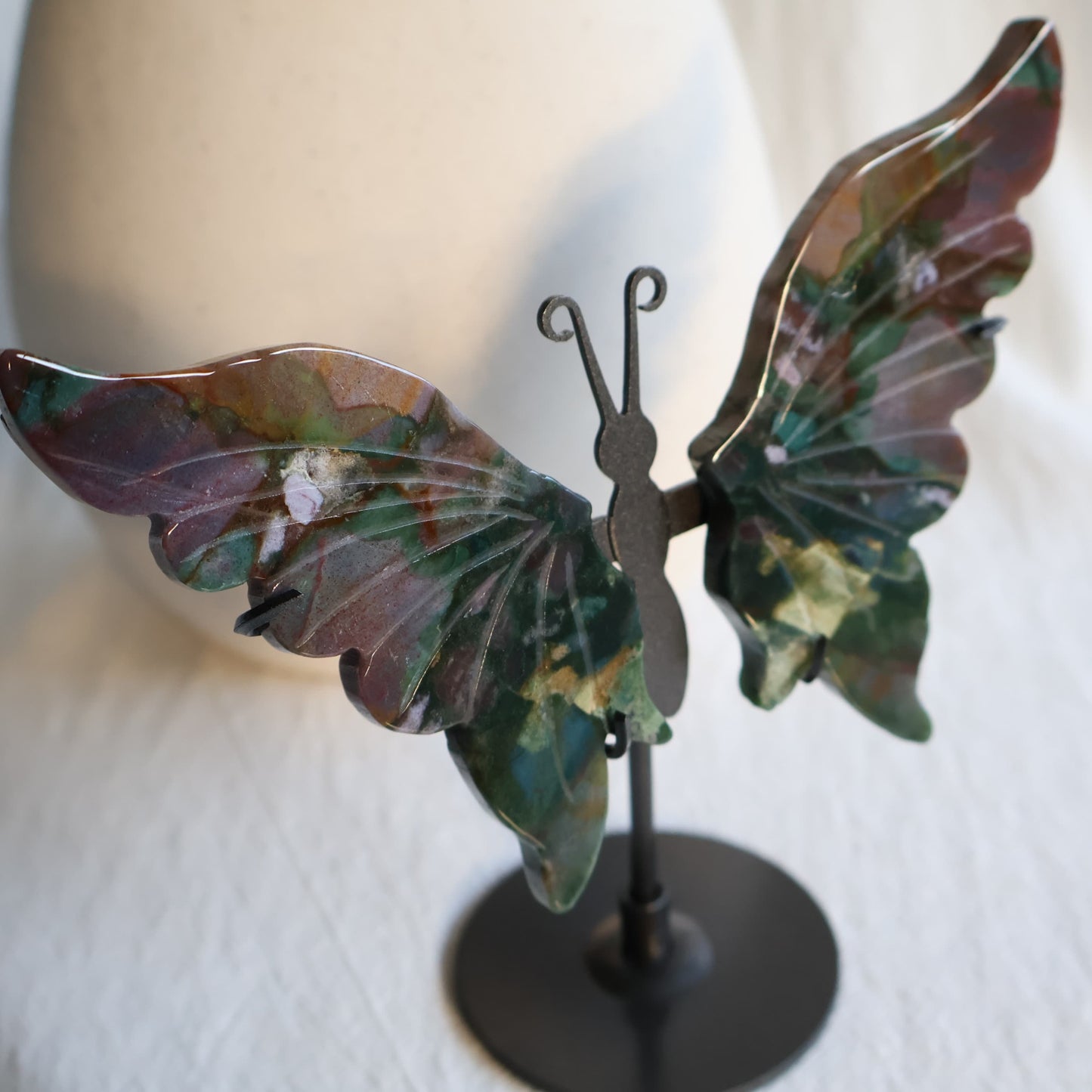 Ocean Jasper butterfly wings on black metal stand with deep green, burgundy, pink and cream natural patterning and polished carved detail