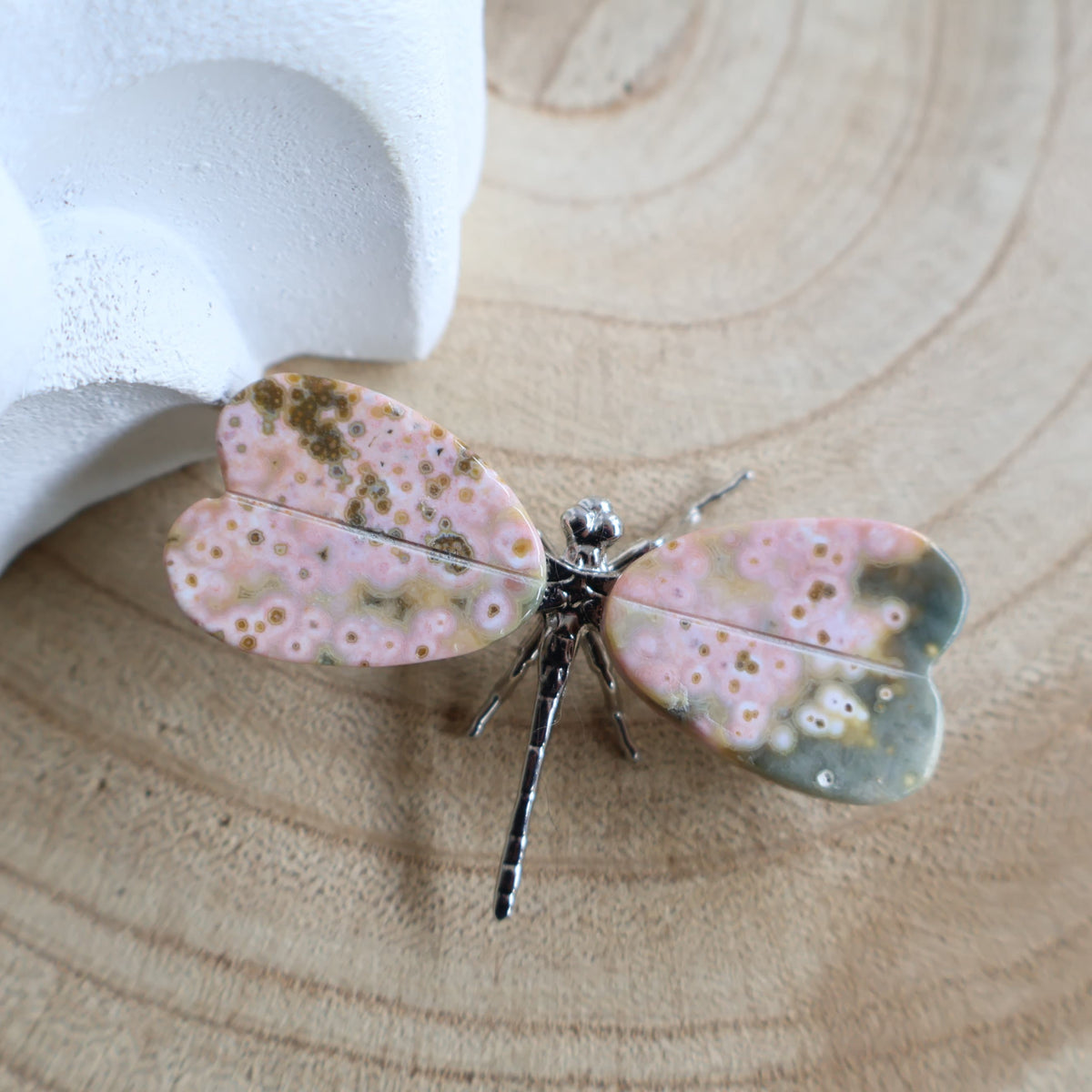 Ocean Jasper dragonfly carving, 6cm wide, with pink and green orbicular crystal wings and a silver-toned metal body.