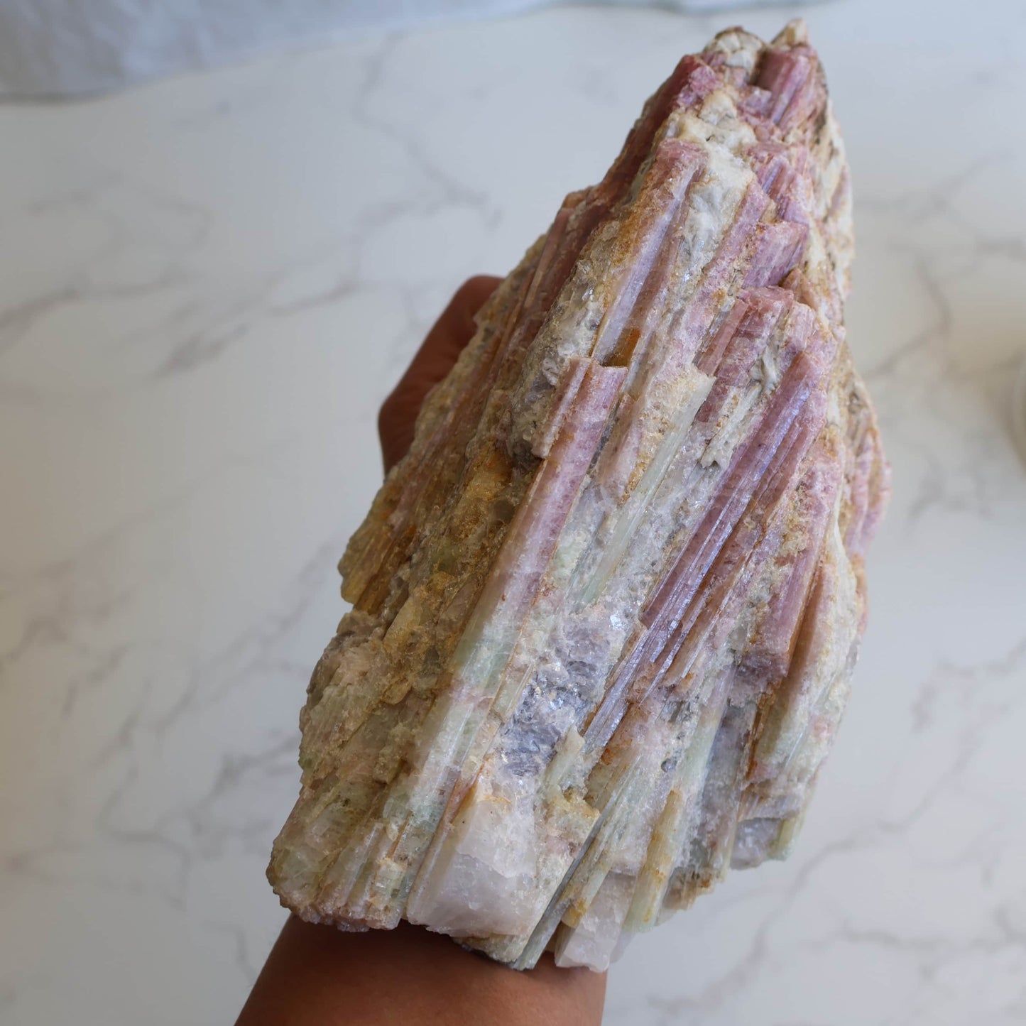 Large pink tourmaline in quartz matrix specimen with elongated pink tourmaline crystals running through white quartz and feldspar matrix displayed on a stand.