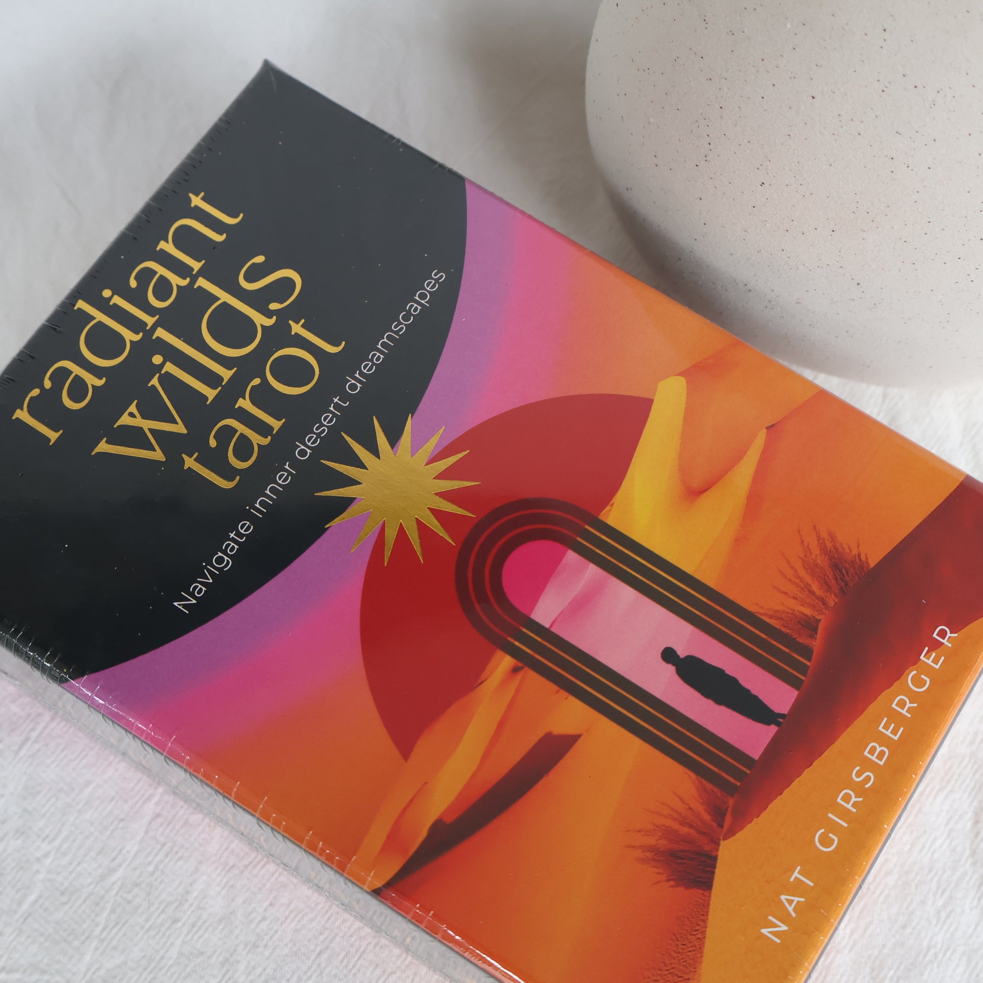 Book titled 'Radiant Wilds Tarot' by Nat Girsberger on a white surface
