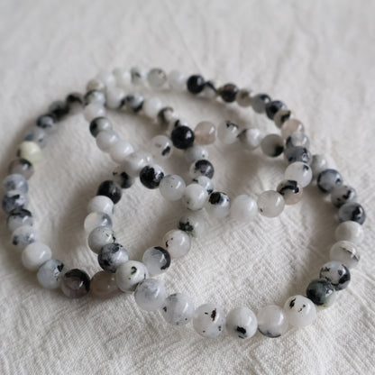 Natural Rainbow Moonstone 6mm crystal bead bracelet with soft white tones and flashes of blue iridescence on a stretch cord.