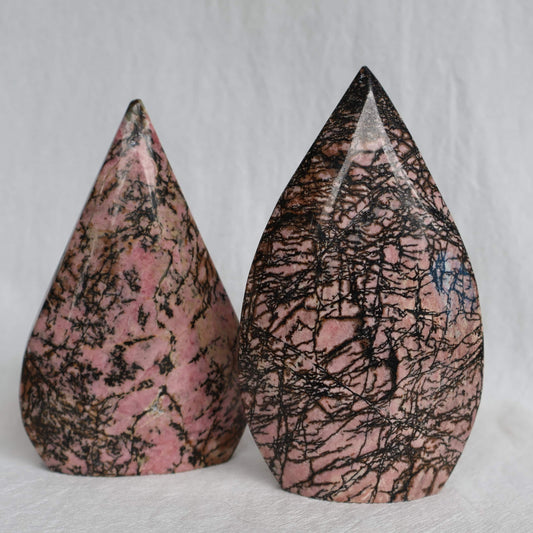 Pink Rhodonite teardrop carving with natural black veining and markings, polished into a smooth freestanding display piece.