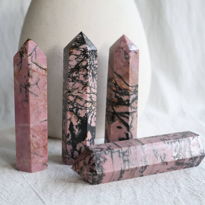 Pink Rhodonite crystal generator with natural black manganese veining and earthy patterning, polished into a pointed tower.