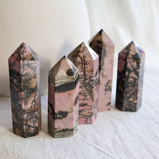 Pink Rhodonite crystal generator with natural black manganese veining and earthy patterning, polished into a pointed tower.