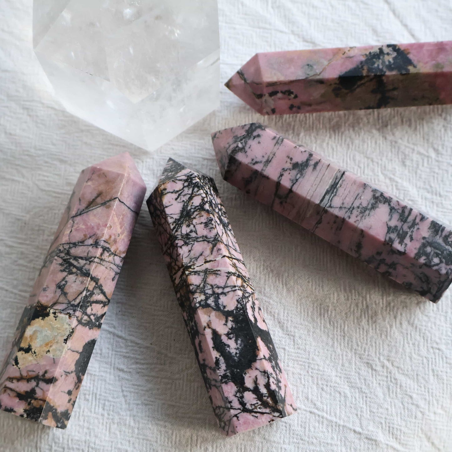 Pink Rhodonite crystal generator with natural black manganese veining and earthy patterning, polished into a pointed tower.