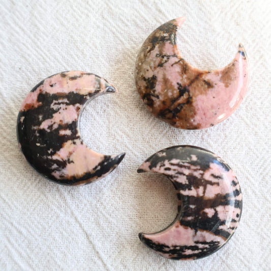 Small 3cm Rhodonite crystal moon carving with natural pink and dark manganese markings.