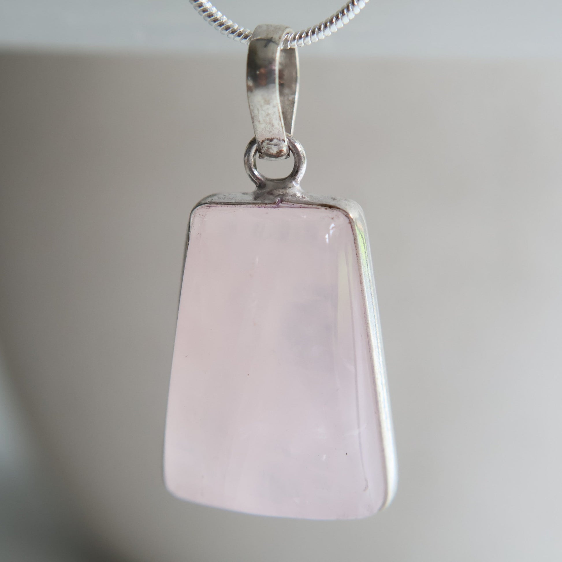 Rose quartz crystal pendant with soft pink tones and wrapped s925 silver border, exact piece shown
