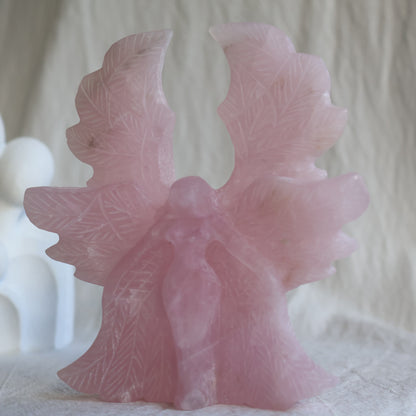 Large Rose Quartz angel crystal carving, 12cm tall and 11cm wide, with detailed feathered wings.