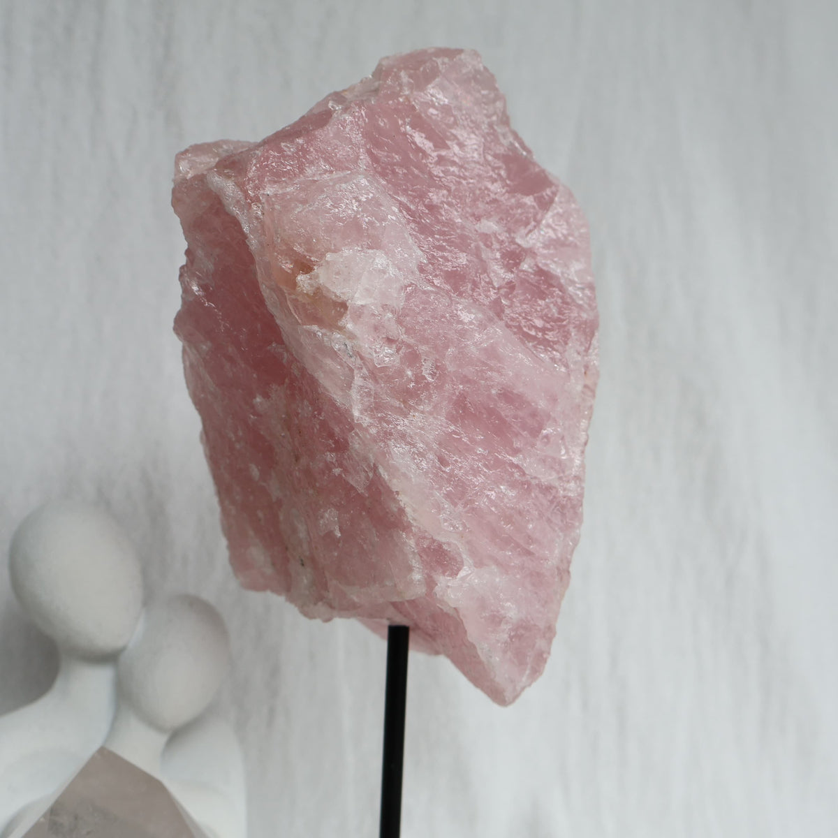 Large 1.1kg raw Rose Quartz crystal on black rotating stand with natural soft pink colouring and raw texture, standing 24cm tall.