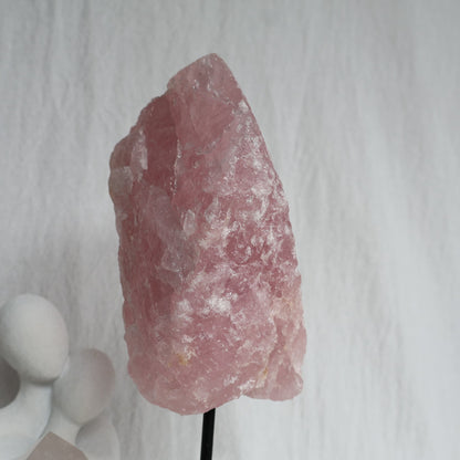 Large 1.1kg raw Rose Quartz crystal on black rotating stand with natural soft pink colouring and raw texture, standing 24cm tall.