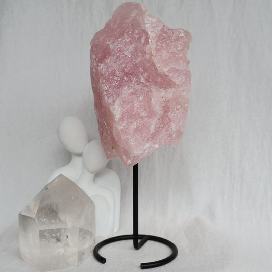 Large 1.1kg raw Rose Quartz crystal on black rotating stand with natural soft pink colouring and raw texture, standing 24cm tall.
