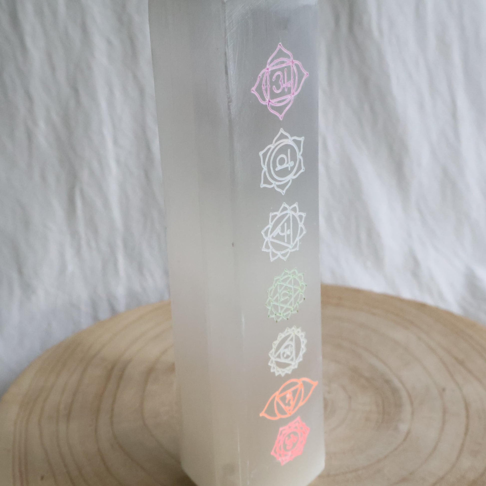 Large white Satin Spar crystal tower engraved with seven coloured chakra symbols from root to crown.