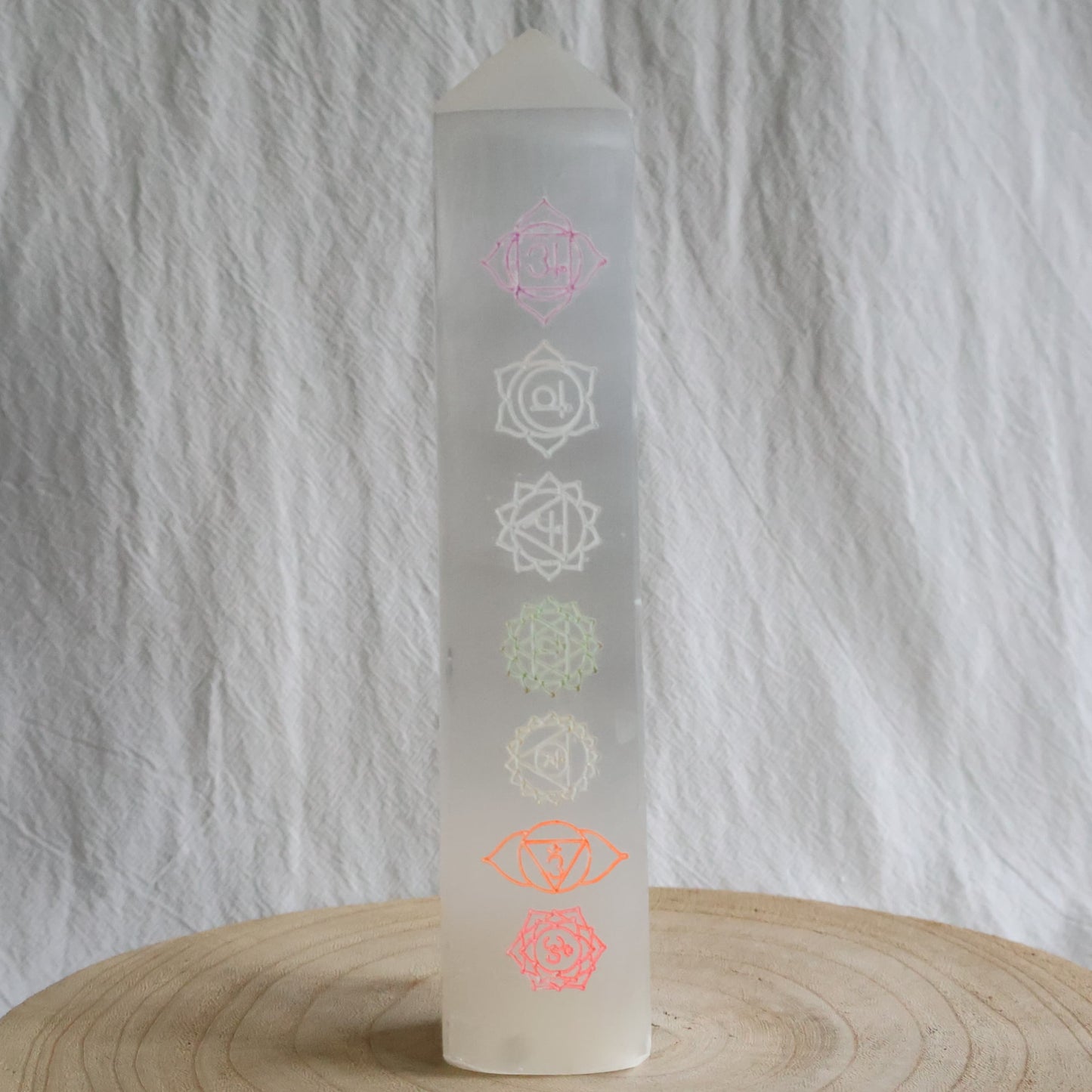 Large white Satin Spar crystal tower engraved with seven coloured chakra symbols from root to crown.