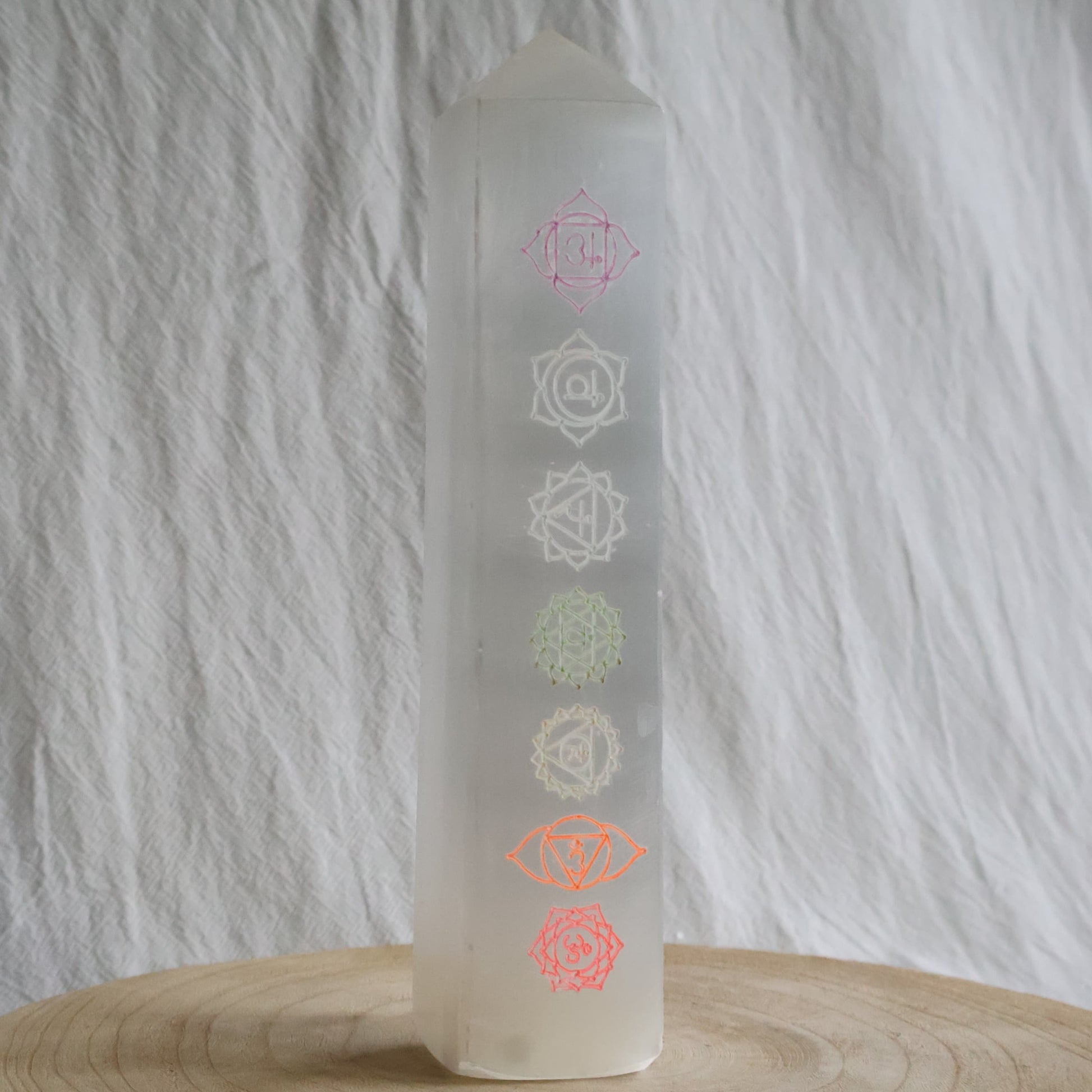Large white Satin Spar crystal tower engraved with seven coloured chakra symbols from root to crown.