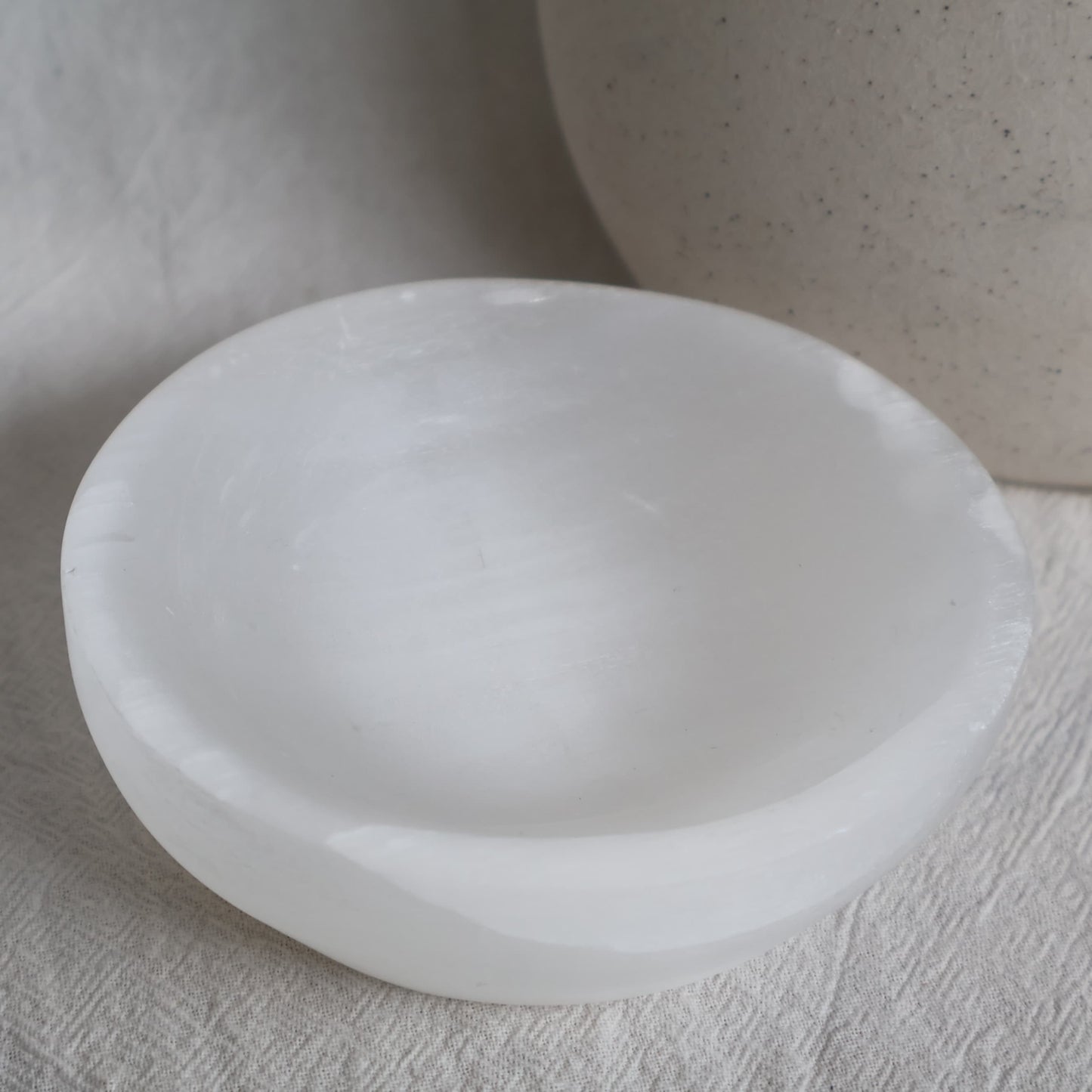 Round Satin Spar crystal bowl approximately 10cm wide with luminous white colouring and a natural silky, pearly sheen.