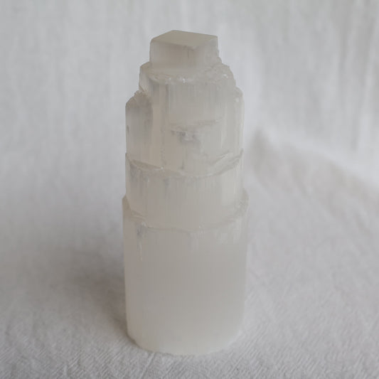 Satin Spar carved crystal tower approximately 10cm tall with luminous white colouring and natural silky fibrous striations.