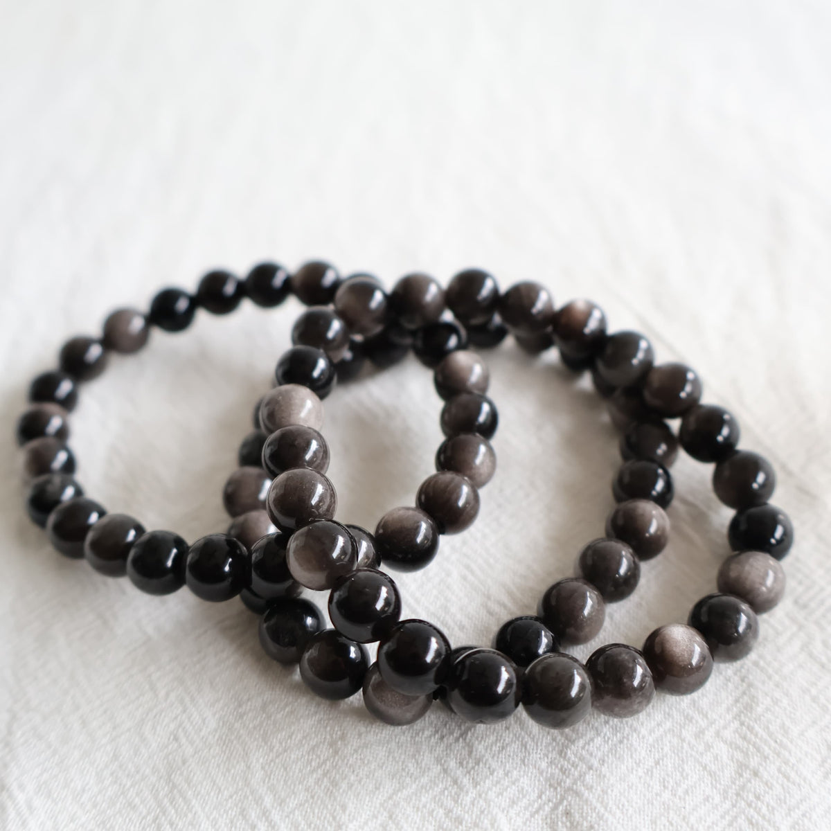 Silver Sheen Obsidian crystal bracelet with polished 8mm round beads on a stretch fit band.